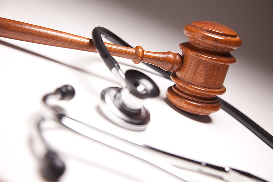 A judge 's gavel and stethoscope on top of a table.