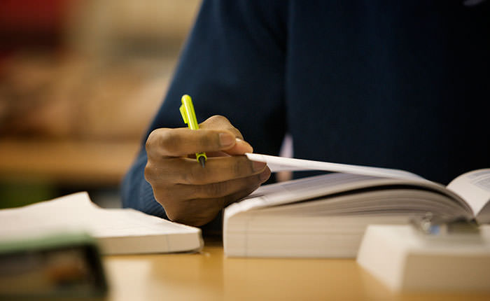 A person writing on some paper with a pen